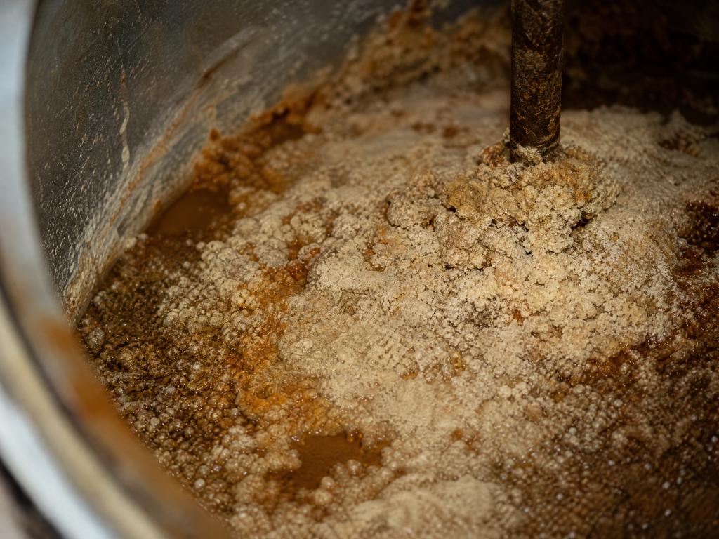 Close-up of brownish-white mineral sediment and calcium scale deposits inside the bottom of a water heater tank caused by San Antonio hard water